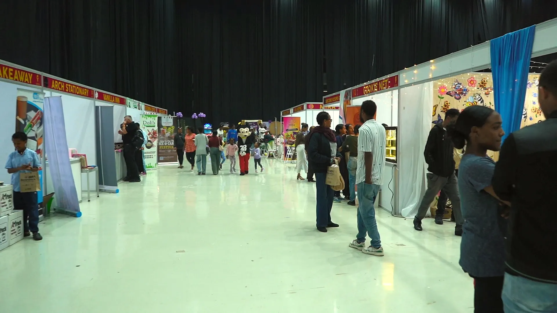 A long aisle of booths with visitors