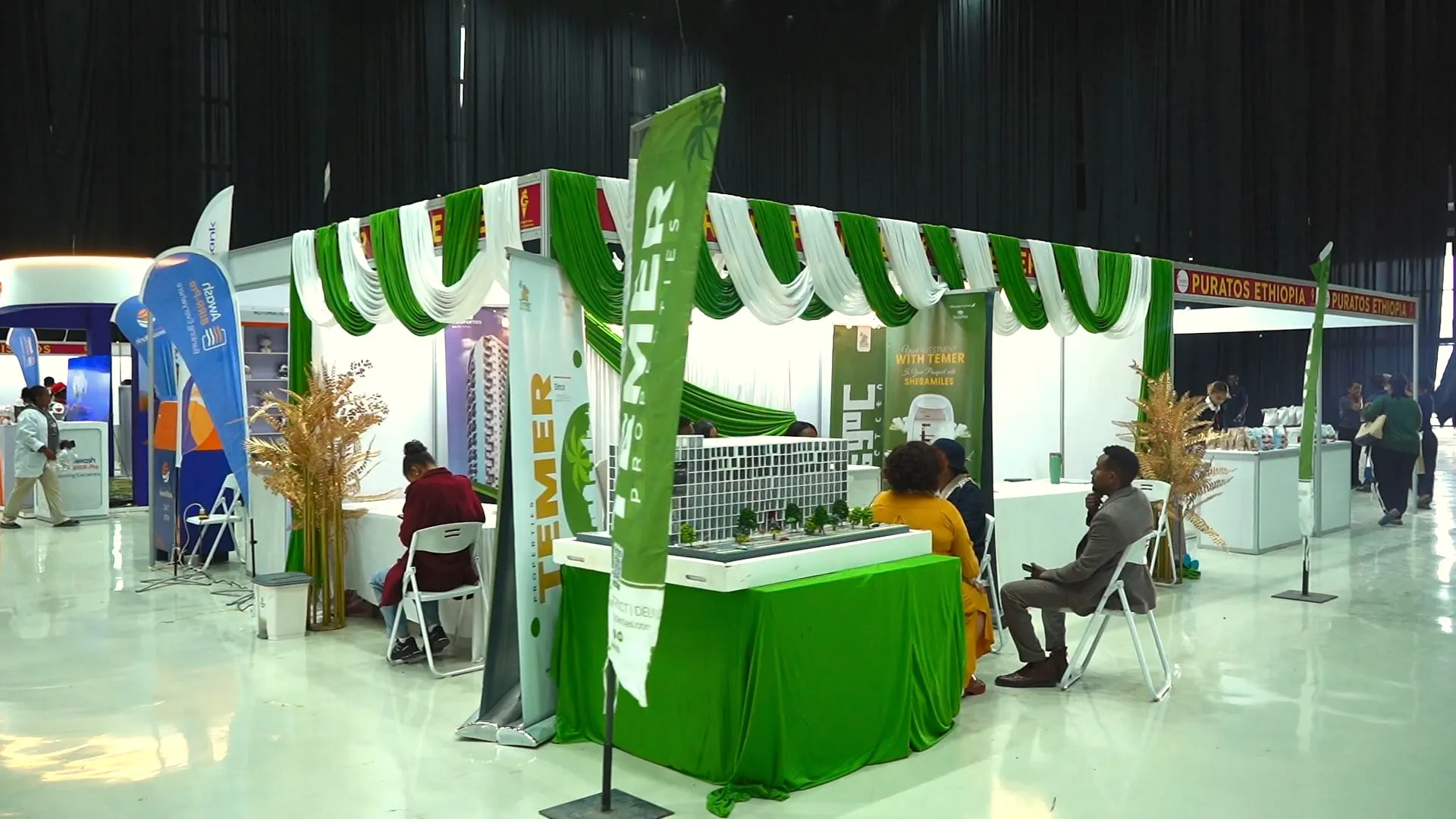 A green-and-white exhibitor booth with flags