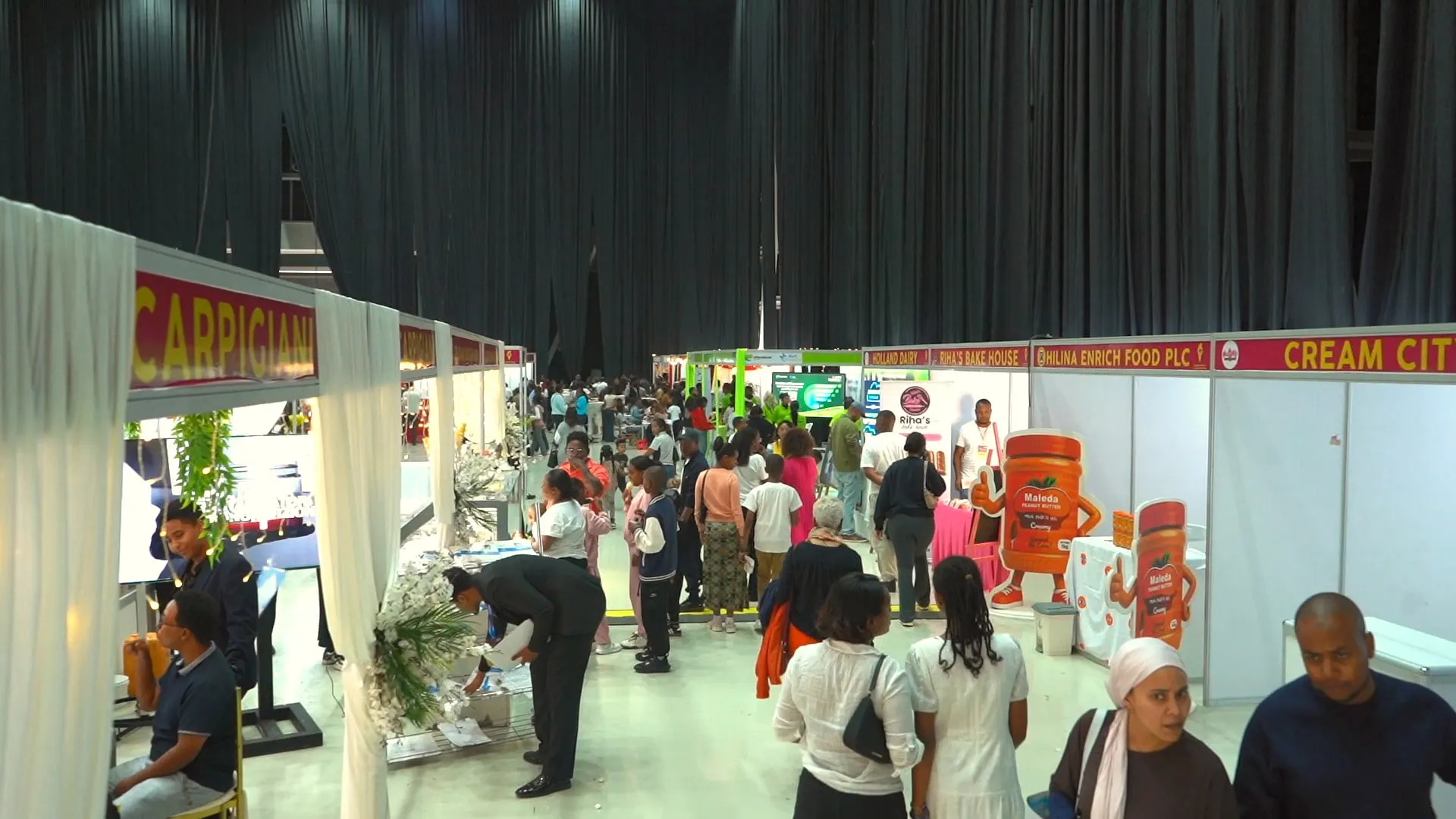A row of booths with visitors browsing