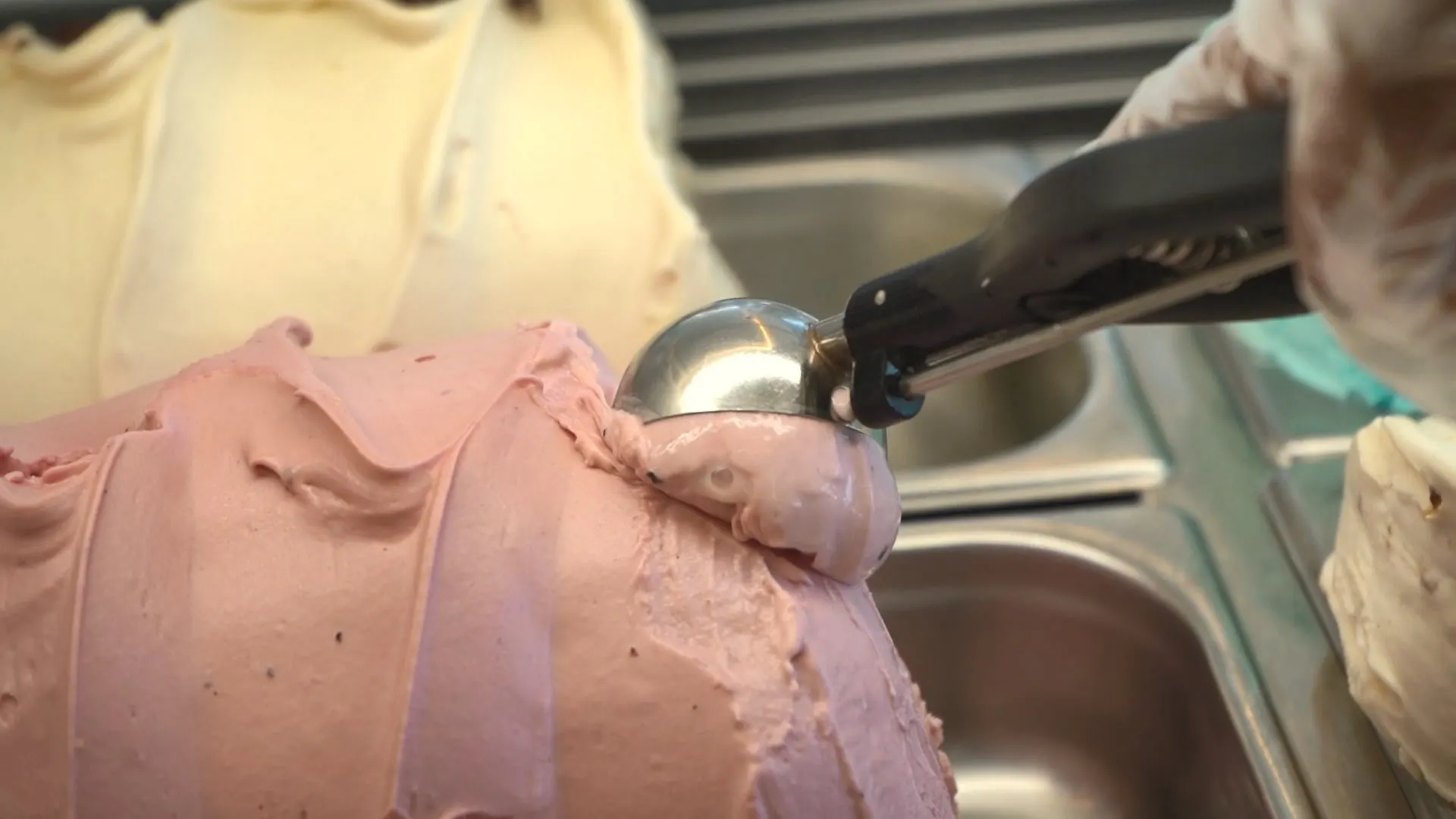 A scoop of strawberry gelato on a metal scoop