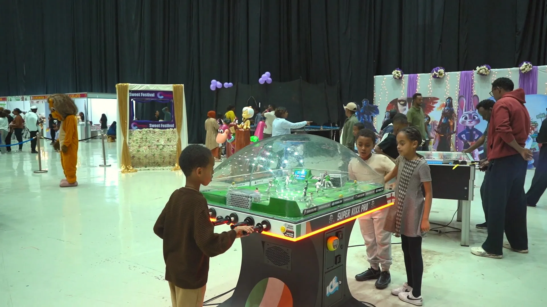 Kids playing table games beside a mascot
