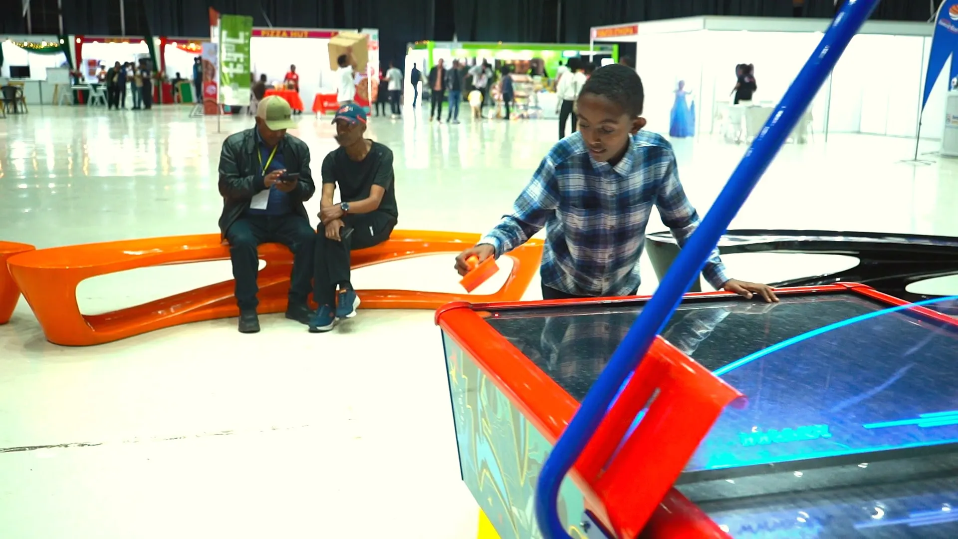 Visitors relaxing on orange lounge seating beside the arcade