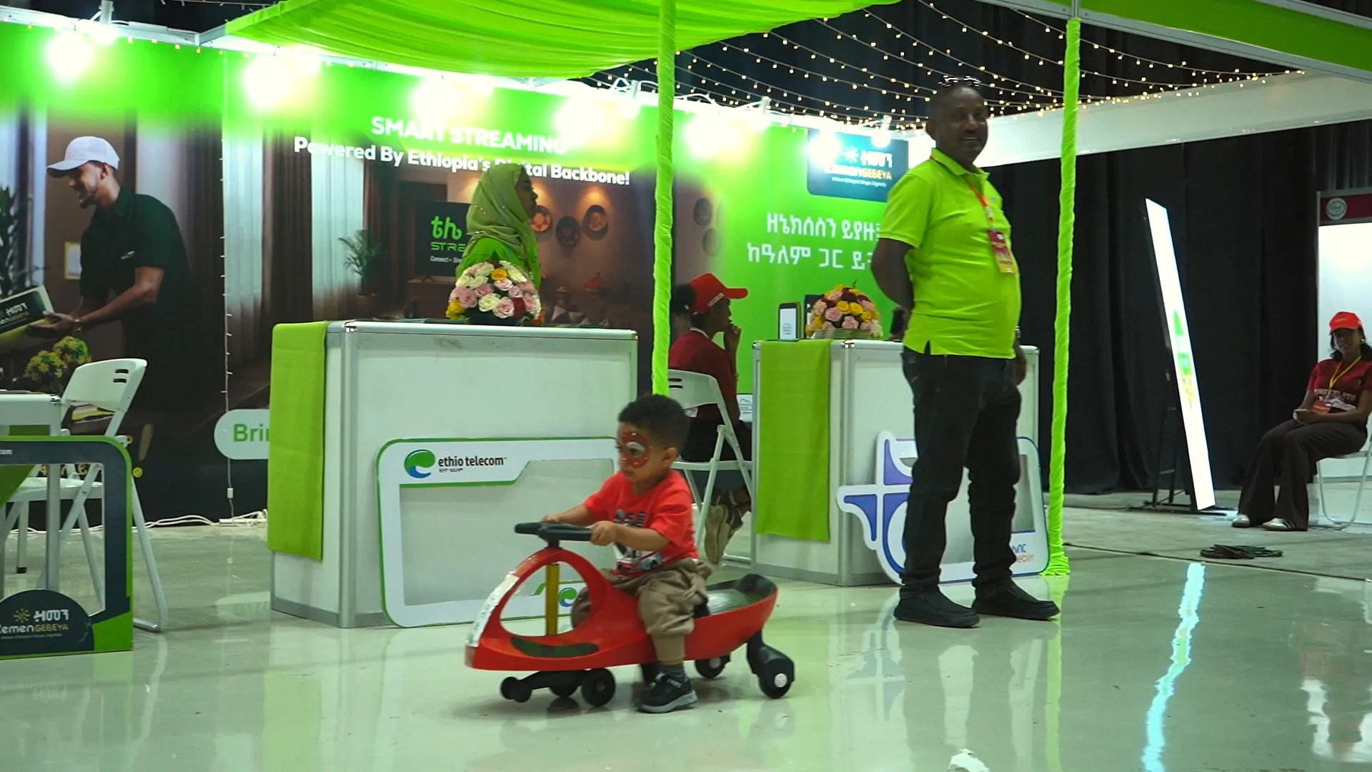 A child on a ride-on car in front of a green booth